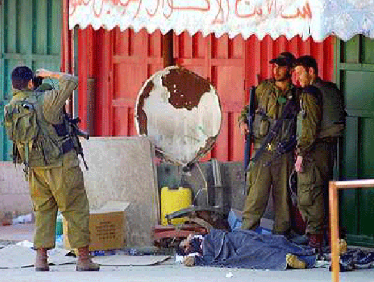 3 Jewish soldiers take a souvenir photo above a dead Palestinian.